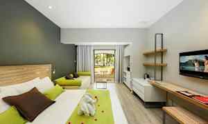 Modernt hotellrum med säng, skrivbord, soffa och utsikt mot en trädgård. (AI-genererad text)