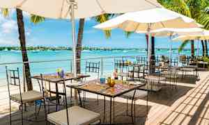 Utomhus restaurang vid havet med bord, stolar och parasoller. (AI-genererad text)