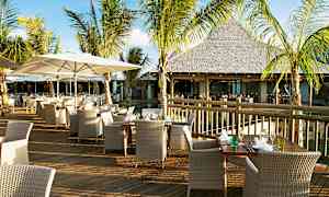 Utomhusrestaurang med bord och stolar på en träterrass omgiven av palmer. (AI-genererad text)