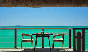 Ett dukat bord med två stolar på en uteplats med havsutsikt. (AI-genererad text)