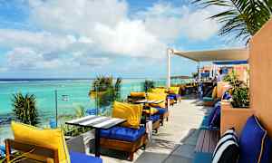 Uteservering med solstolar och bord vid havet. (AI-genererad text)