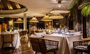 En elegant restaurang med dukade bord och rottinglampor. (AI-genererad text)