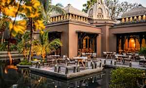 En utomhusmiljö med bord och stolar vid en byggnad med domed tak. (AI-genererad text)