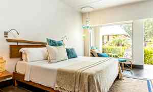 Ett ljust sovrum med en dubbelsäng och stora fönster ut mot en grönskande trädgård. (AI-genererad text)