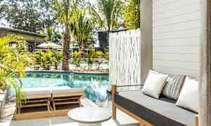 Utomhusområde med pool, solstolar och en soffa med kuddar. (AI-genererad text)