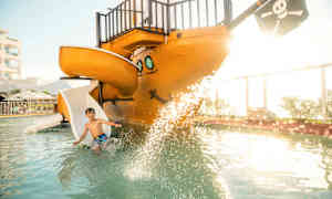 Barn leker i en pool med ett piratskepp som har en rutschkana. (AI-genererad text)