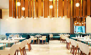 En modern restaurang med eleganta stolar och bord. Dekorativa ljuskällor hänger från taket. (AI-genererad text)