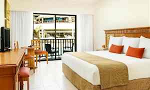 Hotelrum med stor säng, skrivbord och sittgrupp. Glasdörr som leder till en balkong med utsikt över poolområde. (AI-genererad text)