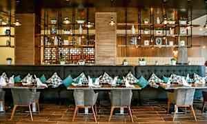 Restaurangmiljö med bord, stolar, och väggar med dekoration och hyllor. (AI-genererad text)