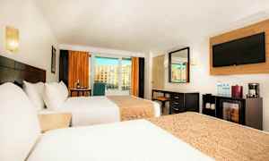Hotellrum med två sängar, ett skrivbord, en tv och stora fönster med utsikt. (AI-genererad text)