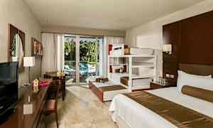 Hotellrum med sängar, skrivbord och utsikt mot en balkong med grönska. (AI-genererad text)