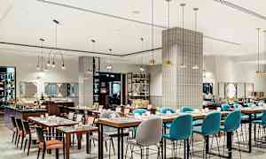 En modern restaurang med dukade bord och stolar, samt taklampor som hänger ned från taket. (AI-genererad text)