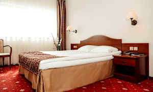 Hotellrum med en säng, sängbord och gardiner. (AI-genererad text)