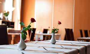 Ett elegant dukat matbord prytt med en vit vas som innehåller en enda röd ros. (AI-genererad text)