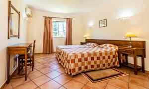 Ett hotellrum med två enkelsängar och ett skrivbord intill väggen. (AI-genererad text)