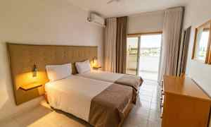 Ett hotellrum med två enkelsängar, en byrå och ett utgång till en balkong. (AI-genererad text)