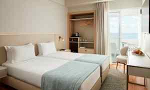 Ett hotellrum med två enkelsängar och havsutsikt. (AI-genererad text)