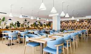 Restaurang med blå stolar och träbord, omgiven av växter. (AI-genererad text)