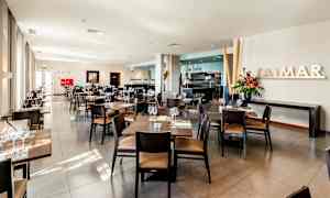 En ljus och modern restaurang med bord och stolar prydligt arrangerade, färska blommor och stora fönster. (AI-genererad text)