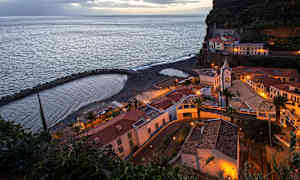 En kuststad med byggnader och en liten strand under kvällstid. (AI-genererad text)