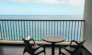 Två stolar och ett bord på en balkong med havsutsikt. (AI-genererad text)