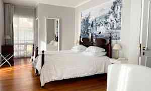 Ett hotellrum med två enkelsängar, trägolv och en stor väggmålning. (AI-genererad text)