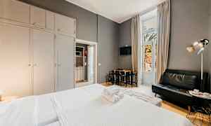 Hotellrum med säng, soffa och matbord, stora garderober samt en balkongdörr. (AI-genererad text)