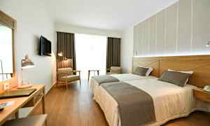 Hotelrum med två enkelsängar, skrivbord och sittplatser. (AI-genererad text)