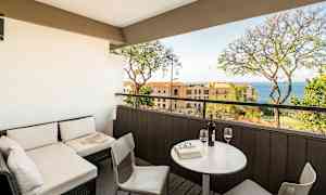 En terrass med sittgrupp och utsikt mot havet, med bord och två glas vin. (AI-genererad text)