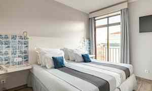 Ett hotellrum med två sängar, blå dekorativa kuddar och en fönsterutsikt. (AI-genererad text)