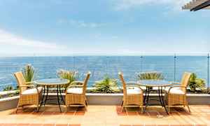 En terrass med möbler av rotting och utsikt över havet. (AI-genererad text)