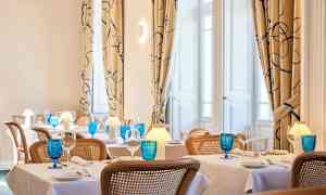 Bild av en elegant restaurang med dukade bord, blå glas och varm belysning. (AI-genererad text)