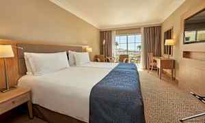 Hotellrum med två enkelsängar och en balkong med utsikt. (AI-genererad text)