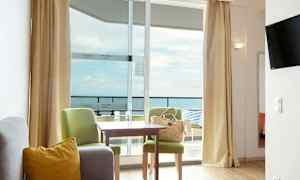 Ett hotellrum med sittgrupp och utsikt mot havet. (AI-genererad text)