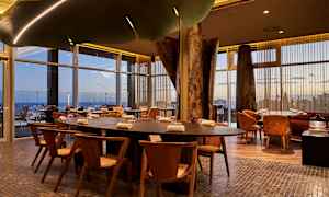 Bord och stolar i en modern restaurang med stora glasfönster. (AI-genererad text)