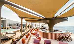 Modernt poolområde med skuggande tak, solstolar och utsikt över havet. (AI-genererad text)