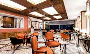 En elegant lounge med röda stolar, ett marmorgolv och trädetaljer i taket. (AI-genererad text)