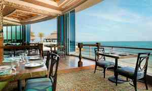 En restaurang med utsikt över havet, med inglasning och eleganta borddukningar. (AI-genererad text)