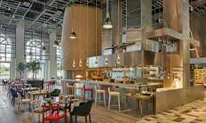 En restaurang med ett öppet kök, modern inredning och sittplatser med olika färger och design. (AI-genererad text)