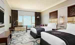 Ett hotellrum med två sängar, skrivbord och utsikt mot havet. Väggdekoration och elegant inredning. (AI-genererad text)