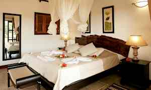 Hotellrum med dubbelsäng, dekorerat med blommor och handdukar. (AI-genererad text)