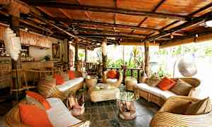 En tropisk inredd sittgrupp med korgmöbler och orange kuddar. (AI-genererad text)