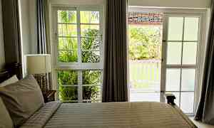 Ett sovrum med fönster och dörr som vetter ut mot en trädgård. (AI-genererad text)