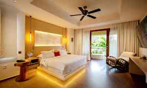 Ett modernt sovrum med en stor säng, sittplatser och en öppen balkong med utsikt över grönska. (AI-genererad text)