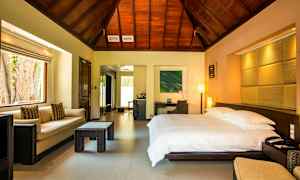 Ett hotellrum med en stor säng, soffa och bord, träpanel i taket. (AI-genererad text)