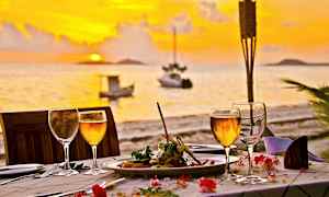 Middag på en dukad bord vid solnedgången med havet i bakgrunden. (AI-genererad text)