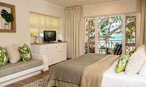 Bild av ett hotellrum med ett bekvämt dubbelsäng och ett sittområde, en tv på en vit möbel och utsikt mot havet från en balkong med möbler. (AI-genererad text)