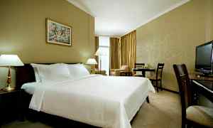 En hotellrum med en stor bäddad säng, lampor, matbord och en TV. (AI-genererad text)