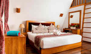 Ett stilrent sovrum med en dubbelsäng, trädetaljer och dekorerade kuddar. (AI-genererad text)