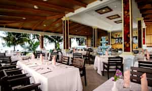 Bild av en restaurang med dukade bord och utsikt mot en grönskande utomhusmiljö. (AI-genererad text)